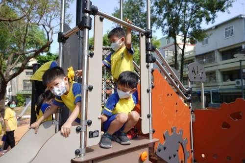 幼兒園孩童開心地體驗公園溜滑梯。